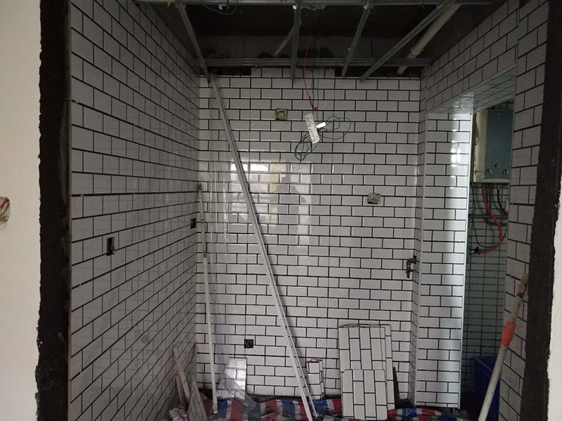 廁所裝修貼瓷磚案例：首先應(yīng)全部清理墻面上的各類污物，打掃干凈現(xiàn)場(chǎng)，特別是腳落里；然后用泥刀先批墻，后用水泥漿找平。這個(gè)工序很重要，確保底子平，防止貼后空鼓；以及墻面要刷防水涂料，防止貼后浸水，一般高度不低于1.8米，刷的時(shí)候會(huì)稍高一些；接著把粘結(jié)劑漿料均勻的刮到墻上，記得瓷磚上墻將經(jīng)過(guò)預(yù)先清潔的瓷磚平整地鋪貼在粘結(jié)劑漿料基層上，使用橡膠錘將瓷磚拍實(shí)鋪平。施工過(guò)程中，可小幅度轉(zhuǎn)動(dòng)瓷磚，使?jié){料與瓷磚背面充分接觸。