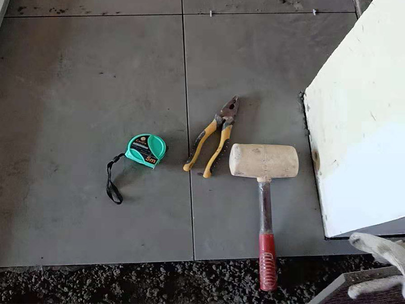 客廳地磚鋪貼：鋪貼的工具包括橡膠錘和粘結(jié)劑。在進(jìn)行施工之前先把所需要的這些材料都整理好放在一旁備用；基層的處理工作對瓷磚的平整度有很大的影響，對于基層要做好清潔工作，還有找平工作。放樣：在進(jìn)行瓷磚的鋪貼工作之前還事先找好垂直線，這樣可以在鋪貼的時候找到瓷磚的水平線，讓瓷磚鋪貼的更加的平整。粘結(jié)劑加水?dāng)嚢杈鶆?，靜置10分鐘之后就可以使用。將瓷磚表面的浮灰清除，再在瓷磚背面均勻的涂抹上粘結(jié)劑，按照預(yù)鋪的順序?qū)⒋纱u鋪貼在地面上，最后用橡膠錘輕輕拍打至服帖齊整。