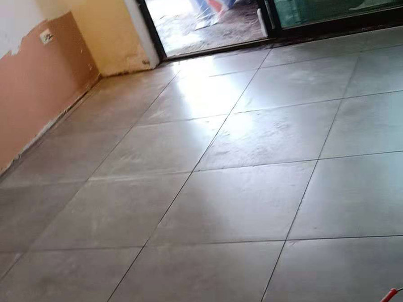 客廳地磚鋪貼：鋪貼的工具包括橡膠錘和粘結(jié)劑。在進(jìn)行施工之前先把所需要的這些材料都整理好放在一旁備用；基層的處理工作對瓷磚的平整度有很大的影響，對于基層要做好清潔工作，還有找平工作。放樣：在進(jìn)行瓷磚的鋪貼工作之前還事先找好垂直線，這樣可以在鋪貼的時候找到瓷磚的水平線，讓瓷磚鋪貼的更加的平整。粘結(jié)劑加水?dāng)嚢杈鶆?，靜置10分鐘之后就可以使用。將瓷磚表面的浮灰清除，再在瓷磚背面均勻的涂抹上粘結(jié)劑，按照預(yù)鋪的順序?qū)⒋纱u鋪貼在地面上，最后用橡膠錘輕輕拍打至服帖齊整。