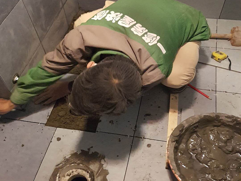 廁所貼地磚： 1、基層處理：把沾在基層上的浮漿、落地灰等用暫子或鋼絲刷清理掉，再用掃帚將浮土清掃干凈。 2、找標(biāo)高：根據(jù)水平標(biāo)準(zhǔn)線和設(shè)計(jì)厚度，在四周墻、柱上彈出面層的上平標(biāo)高控制線。 3、排磚：將房間依照磚的尺寸留縫大小，排出磚的放置位置，并在基層地面彈出十字控制線和分格線。 4、鋪設(shè)結(jié)合層砂漿：鋪設(shè)前應(yīng)將基底濕潤(rùn)，并在基底上刷一道素水泥漿或界面結(jié)合劑，隨刷隨鋪設(shè)攪拌均勻的干硬性水泥砂漿。 5、鋪磚：將磚放置在于拌料上，用橡皮錘找平，之后將磚拿起，在干拌料上澆適量素水泥漿，同時(shí)在磚背面涂厚度約lnm的素水泥膏，再將磚放置在找過(guò)平的干拌料上，用橡皮錘按標(biāo)高控制線和方正控制線坐平坐正。 6、鋪磚時(shí)應(yīng)先在房間中間按照十字線鋪設(shè)十字控制磚，之后按照十字控制磚向四周鋪設(shè)，并隨時(shí)用2m靠尺和水平尺檢查平整度。大面積鋪貼時(shí)應(yīng)分段、分部位鋪貼。 7、養(yǎng)護(hù)：當(dāng)磚面層鋪貼完24h內(nèi)應(yīng)開(kāi)始澆水養(yǎng)護(hù)，養(yǎng)護(hù)時(shí)間不得小于7d。