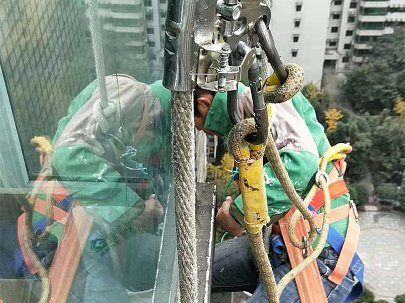 高空外墻施工：1、目前外墻粉刷主要有兩種方式：吊板方式和吊籃方式。 2、吊板方式是用吊繩、吊板將人吊到工作位置進行清洗。一般的大樓都可以用這種方式進行清洗，但是這種方式的操作必須使安全措施到位，否則危險性很大，造成傷亡事故的都是因安全措施不到位造成的。 3、墻面破損、裂縫、不平整等部位在底涂前用外墻耐水膩子修補平整。每次批刮膩子的厚度控制在2mm之內，批刮膩子的總厚度不超過5mm。膩子應堅實牢固，不得粉化、起皮或干裂。 4、干后，要用砂紙打磨平整，再用濕布將膩子上的浮灰抹去，并盡快涂漆，以免再次落灰。