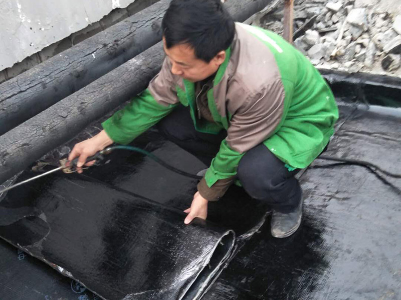 屋頂貼防水卷材：首先做好基礎(chǔ)準(zhǔn)備工作，清理基層，施工前將驗收合格的基層表面塵土、建筑雜物清理干凈。接著涂刷基層處理劑，高聚物改性瀝青卷材施工，攪拌均勻后，用長把滾刷均勻涂刷于基層表面上，常溫經(jīng)過4h后，開始鋪貼卷材。熱熔封邊，將卷材搭接處用噴槍加熱，趁熱使二者粘結(jié)牢固，以邊緣擠出瀝青為度；末端收頭用密封膏嵌填嚴(yán)密。防水層蓄水試驗，卷材防水層完工后，確認(rèn)做法符合設(shè)計要求，將所有雨水口堵住，然后灌水，水面應(yīng)高出屋面最高點20㎜，24h后進行認(rèn)真觀察，尤其是管根、風(fēng)道根，不滲不漏為合格，否則應(yīng)進行返工。