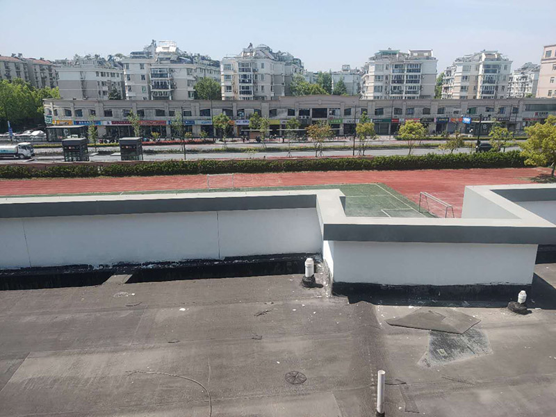 學(xué)校屋頂防水：屋頂做防水前，要先對(duì)需要防水施工的屋頂基層進(jìn)行清潔，因?yàn)楹芏喾浪┕ぶ幸苊庖恍╇s物、塵土等，打掃干凈了更有利于防水施工效果。屋頂防水施工就與室內(nèi)防水施工差不多，室內(nèi)的地漏、水管位置等都要重點(diǎn)涂刷，而屋頂中的水落口、女兒墻、檐口、陰陽角等位置也要先進(jìn)行針對(duì)性的施工，也被稱為附加層施工。屋頂施工防水需要不少材料，特別是防水用的改性瀝青卷材、防水涂料等等，先對(duì)基層鋪貼一層防水卷材，其厚度要符合要求，尺寸根據(jù)屋頂面積進(jìn)行裁剪。卷材一般歐式用熱熔的方式來鋪貼，也就是需要借助火焰噴槍來加熱進(jìn)行滾鋪、粘貼，卷材從檐口處與屋脊平行的方向由下而上進(jìn)行鋪貼。卷材的各個(gè)搭接處都要用噴槍來加熱粘結(jié)牢固，并且在邊緣末端收頭處要用密封膏來嵌填嚴(yán)密好才行。卷材鋪貼好后，要再一次進(jìn)行屋頂清潔，保障干凈、干燥的施工環(huán)境，這時(shí)候就可以進(jìn)行第一層的防水涂料刷涂了，第一遍一定要涂滿，不能出現(xiàn)遺漏、裂紋、氣泡、黏合不牢固等現(xiàn)象。