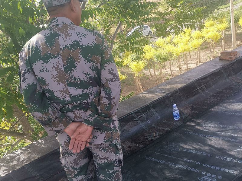 屋頂防水卷材鋪貼:清除基層表面雜物、油污、砂子，凸出表面的石子、砂漿疙瘩等應(yīng)清理干凈，清掃工作必須在施工中隨時(shí)進(jìn)行，并修補(bǔ)平整表面。尤其鏟除排水口、煙囪、管壁上的水泥砂漿等附著物；根據(jù)施工現(xiàn)場(chǎng)狀況，進(jìn)行合理定位，確定卷材鋪貼方向，在基層上彈好卷材控制線，依循流水方向從低往高進(jìn)行卷材試鋪。卷材試鋪后，先將要鋪貼的卷材剪好，反鋪于基面上(即是底部隔離紙朝上)，撕剝?nèi)ゾ聿母綦x紙。撕剝時(shí)，已剝開(kāi)的隔離紙宜與粘結(jié)面保持45～60度的銳角，防止拉斷隔離紙，盡量保持在自然松弛狀態(tài)，但不要有皺折。