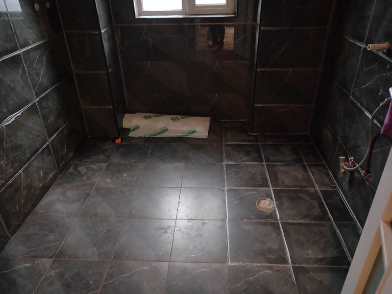 衛(wèi)生間美縫施工：使用用開槽器/平口螺絲刀/勾縫刀，清理瓷磚縫隙內(nèi)灰塵及垃圾，這一步需要力度適中，不要用蠻力，不然可能存在崩壞瓷磚的風(fēng)險(xiǎn)。然后用吸塵器，掃把或者抹布清理干凈。，建議縫隙在1.5到2mm深度合適?？p隙清理干凈后， 擰開管蓋裝上混合管，管頭卡在膠槍的卡口上。裝好混合管后，從下方用美工刀斜切45度角，切記開口要比瓷磚縫隙小，如果本身瓷磚縫隙比較小，可以不用切膠嘴。首先打出30-40CM美縫劑余料，然后沿著瓷磚縫隙開始施工，在施工的時(shí)候一定要美縫劑填充滿瓷磚縫隙，不然后續(xù)可能會(huì)發(fā)生塌陷。瓷磚縫隙打膠方法先豎后橫，沿著縫隙均勻打出美縫劑.一般有些師傅打出3-5米時(shí)停下，開始用壓邊球壓縫，十字交叉口處多壓幾次，這樣會(huì)很美觀。壓縫的工具比較多，可用刮板或者壓縫 鋼球、手指套沿著縫隙壓出 U型面就可以了