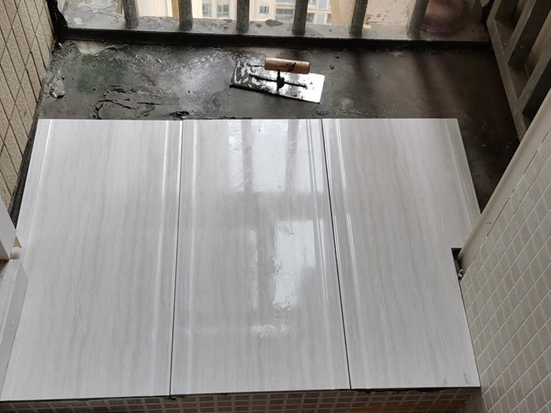 陽臺瓷磚鋪貼：準(zhǔn)備粘結(jié)劑前，瓷磚不應(yīng)浸水，但要用鋼絲刷除去磚背面的松散物質(zhì)，并用濕布抹去磚背的浮塵。然后按照生產(chǎn)商建議的比例將水或乳液放到攪拌桶中攪拌直至粘結(jié)劑均勻無結(jié)塊。初始攪拌后的粘結(jié)劑應(yīng)靜置在攪拌桶中，直到生產(chǎn)商推薦的熟化時間過后攪拌一下再使用。 在鋪壓瓷磚前，在瓷磚背面也批一薄層粘結(jié)劑。這種雙批法雖然用的材料和工時比較多，但卻能夠保證粘貼的質(zhì)量和耐久性。 在粘結(jié)劑量置晾時間內(nèi)，將準(zhǔn)備好的瓷磚鋪壓到位，垂直于梳理方向輕微搓動以排出磚下的空氣。鋪貼到位后用橡皮錘輕擊，用尺寸合適的十字定位架來調(diào)整表面平整度及接縫的平直。