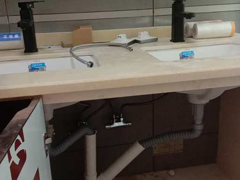 臺盆五金安裝：1.檢查預留給排水管路，安裝支撐洗面盆臺面的鋼制支架。 2.根據臺下盆包裝箱內的臺面切割圖將臺面開孔打磨完畢。 3.按照安裝的龍頭和臺面尺寸正確切割龍頭安裝孔，打磨。 4.把洗面盆暫時放入已開好的臺面安裝口內，檢查間隙，并做好記號。 5.檢查校驗后，把洗面盆放平，在洗臉盆邊緣上口涂上硅膠密封材料后，把洗面盆小心放入臺面下，對準安裝孔，跟先前的記號相校準并向上壓緊，并使用廠家隨貨附帶的臉盆與臺面的連接件，將洗臉盆與臺面緊密連接。 6.臺下盆邊緣打膠。 7.安裝臺下盆上下五金件。 8.等密封膠硬化后，連接進水和排水管件。