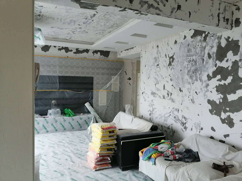 墻面基層刷防固漆：首先我們要把墻體上的工業(yè)大白鏟掉，這種工業(yè)大白是開發(fā)商為了交房刷的一層膩?zhàn)臃郏鼤谏w空鼓裂縫，所以我們需要鏟掉，然后做基層處理，主要是處理空鼓和裂縫，空鼓用錘子敲開然后用水泥砂漿填平，裂縫就用嵌縫帶嵌上。接著刷一層界面劑，這個(gè)界面劑就是黃墻綠地的效果，可以稱為墻固地固，一般毛坯墻中都會含有工業(yè)氨水，而它會持續(xù)不斷的釋放一種有害氣體--氡氣，這個(gè)氡氣對我們的呼吸道和關(guān)節(jié)有一定的危害，所以界面劑一個(gè)作用就是為了防止墻體中的氡氣進(jìn)入室內(nèi)。也可以增加墻面和膩?zhàn)拥母街?，增?qiáng)刷漆質(zhì)量。地固的話可以防止工地灰塵煙塵太大，會影響工人施工，另外也可以防止灰塵附著在某些家具表面，影響后期家具漆的效果。