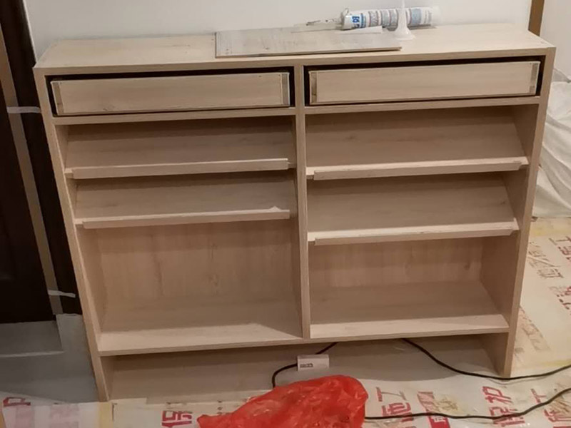 家具柜體安裝：用墊布點(diǎn)好地板，先從靠墻的一端寬du側(cè)板開(kāi)始組裝，將寬側(cè)板平放于地面上(離后墻面保持700mm間隔)。首先將填好的三合一膠塞的板件，平放在墊布上，檢查孔距與圖紙相符，并裝上三合一單連桿。然后將固層釘上木塞，固定于寬側(cè)板上面，頂板大柄孔朝上，其余固層都朝下，腳線(xiàn)大柄孔朝內(nèi)(中間固層與L架高度一致，即底板到固層內(nèi)空為960mm，現(xiàn)場(chǎng)打?qū)影蹇?。放上側(cè)板，釘上木塞，木塞要求連通兩邊的固層。在第二個(gè)柜固層上面裝好雙連桿，留意雙連桿上面大柄只能鎖住一半，即90&deg;。當(dāng)兩件固層與側(cè)板固定后再同時(shí)擰緊大柄。 釘背板：把裝好的整體柜側(cè)放在點(diǎn)好墊布的地板上面，墊平側(cè)板成統(tǒng)一平面。用拉尺量好柜子的對(duì)角尺寸，調(diào)至相等，從寬測(cè)板處開(kāi)始裝第一塊背板，留意假如中間有固層釘釘子時(shí)，先用鉛筆畫(huà)好固層的中央線(xiàn)，再釘釘子。