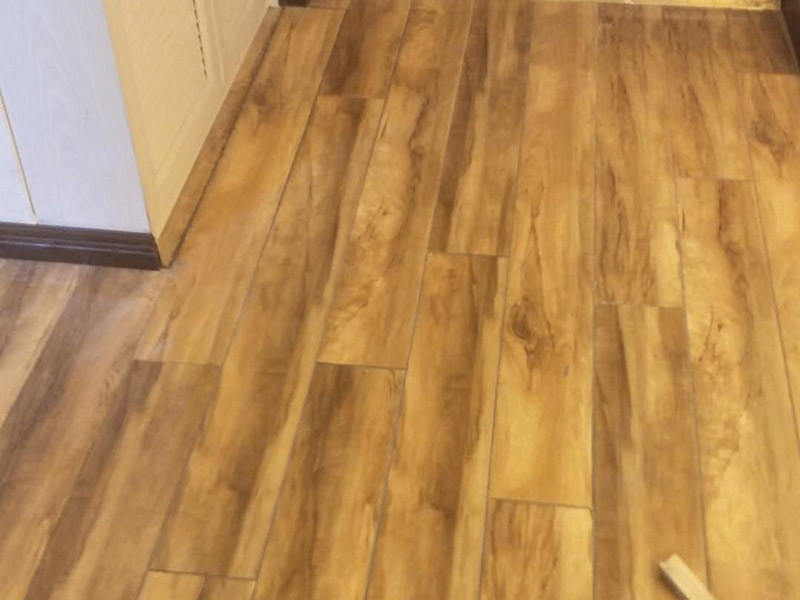 入戶門鋪地板：1、先對地面進(jìn)行找平，水平的誤差不能超過2毫米。地面要是不平，腳感就不好。再就是將邊、角部位等突起或有不平的地方進(jìn)行局部修整。再鋪防潮層，防潮層可以防止以后地板受潮。鋪平，接縫處要并攏。  2、然后就是安裝地板了，因為地板是要錯落安裝的，先預(yù)鋪一下，將部分地板一分為二，要按尺寸來鋸，萬一鋸多了，地板損耗就大了。因為地板有一定的膨脹率，因此鋪裝前要在其與墻面接觸的部位預(yù)留膨脹縫，以免地板起鼓。膨脹縫的大小一般和地板的膨脹系數(shù)有關(guān)系。粘合地板的膠水要用強(qiáng)化地板專用的，這種膠的污染比較小。不要隨便在市場上選非地板專用膠，地板本身就存在的污染上再增加污染源。  3、鋪前看好地板是否用對，再鋪設(shè)地板。在鋪設(shè)時，要一塊短的旁邊鋪一塊長的，這樣交叉鋪設(shè)地板就咬得住不易松動，地板拼合后還要用工具敲緊。再下來就是銜接了，一般用地板壓條掩蓋。但也有用玻璃膠填充。