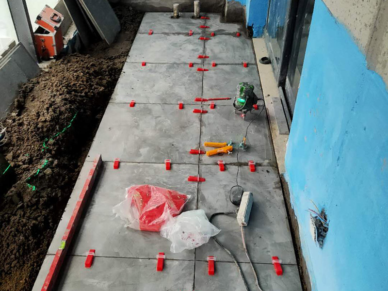 陽臺防水貼磚:在粘結劑量置晾時間內，將準備好的瓷磚鋪壓到位，垂直于梳理方向輕微搓動以排出磚下的空氣。鋪貼到位后用橡皮錘輕擊，用尺寸合適的十字定位架來調整表面平整度及接縫的平直。鋪設好的磚面應該及時清理干凈，特別是去除殘留其上的粘結劑。合格的粘結劑干硬后即使在陶瓷磚面上也不易被清除掉。清理好的瓷磚面應該立即擺放標識進行隔離，避免污染或擾動，直到下一個填縫工序。