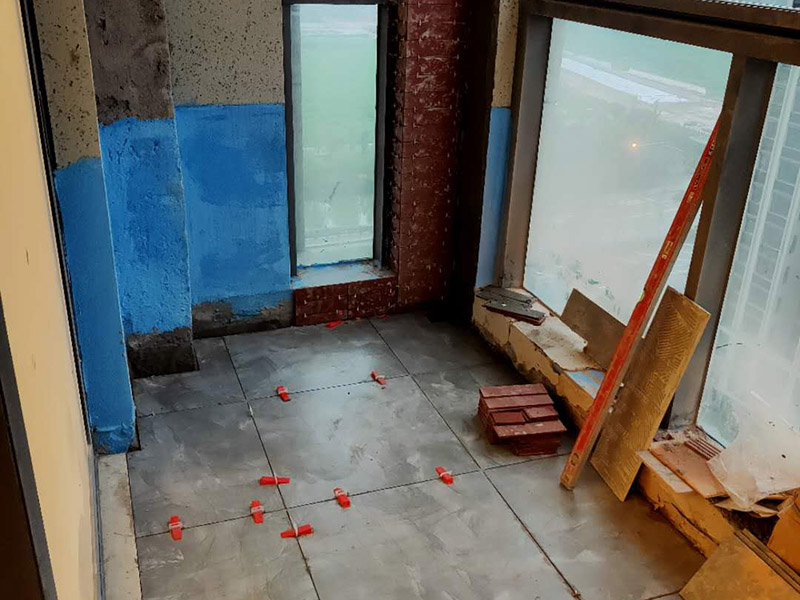 陽臺防水貼磚:在粘結劑量置晾時間內，將準備好的瓷磚鋪壓到位，垂直于梳理方向輕微搓動以排出磚下的空氣。鋪貼到位后用橡皮錘輕擊，用尺寸合適的十字定位架來調整表面平整度及接縫的平直。鋪設好的磚面應該及時清理干凈，特別是去除殘留其上的粘結劑。合格的粘結劑干硬后即使在陶瓷磚面上也不易被清除掉。清理好的瓷磚面應該立即擺放標識進行隔離，避免污染或擾動，直到下一個填縫工序。