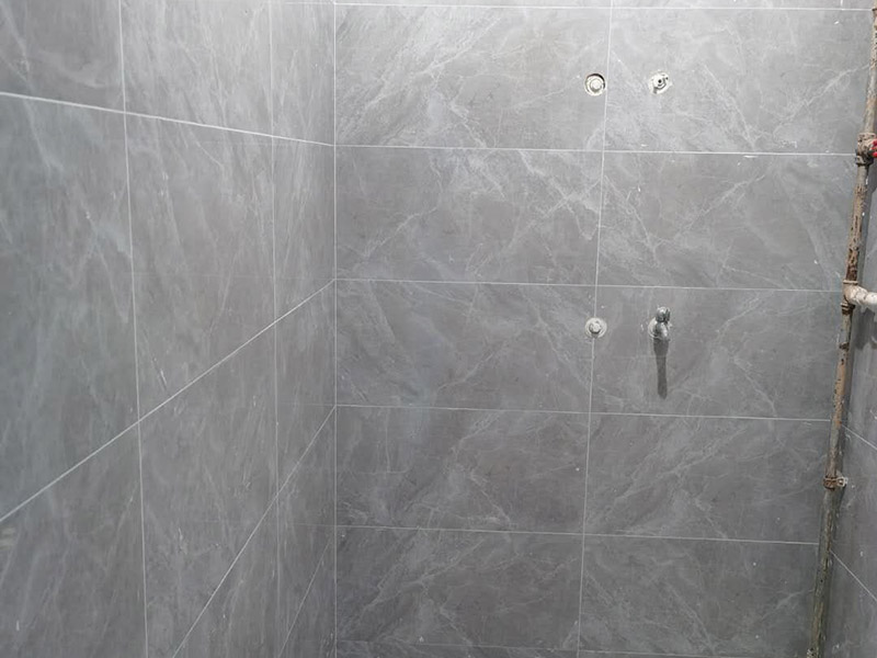 衛(wèi)生間貼磚施工：應(yīng)全部清理墻面上的各類污物，打掃干凈現(xiàn)場(chǎng)，特別是腳落里。用泥刀先批墻，后用水泥漿找平。這個(gè)工序很重要，確保底子平，防止貼后空鼓。墻面要刷防水涂料，防止貼后浸水，一般高度不低于1.8米，刷的時(shí)候會(huì)稍高一些。根據(jù)設(shè)計(jì)鋪貼圖樣的要求，確定排磚方案，用墨斗彈線，以減少施工損耗。把剛剛攪拌好的粘結(jié)劑漿料均勻的刮到墻上。瓷磚上墻將經(jīng)過(guò)預(yù)先清潔的瓷磚平整地鋪貼在粘結(jié)劑漿料基層上，使用橡膠錘將瓷磚拍實(shí)鋪平。施工過(guò)程中，可小幅度轉(zhuǎn)動(dòng)瓷磚，使?jié){料與瓷磚背面充分接觸。專家建議在鋪貼時(shí)，隨機(jī)取下已鋪貼于基層上的瓷磚作檢查。確保漿料與瓷磚背面的充分接觸。 留縫大小調(diào)整根據(jù)瓷磚的尺寸，在磚與磚之間預(yù)留相應(yīng)尺寸的縫隙留待嵌縫。可用牙簽等先固定，粘結(jié)劑具有一定的可調(diào)整性，可對(duì)留縫的大小進(jìn)行調(diào)整。