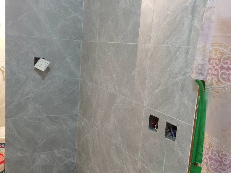 衛(wèi)生間貼磚施工：應(yīng)全部清理墻面上的各類污物，打掃干凈現(xiàn)場(chǎng)，特別是腳落里。用泥刀先批墻，后用水泥漿找平。這個(gè)工序很重要，確保底子平，防止貼后空鼓。墻面要刷防水涂料，防止貼后浸水，一般高度不低于1.8米，刷的時(shí)候會(huì)稍高一些。根據(jù)設(shè)計(jì)鋪貼圖樣的要求，確定排磚方案，用墨斗彈線，以減少施工損耗。把剛剛攪拌好的粘結(jié)劑漿料均勻的刮到墻上。瓷磚上墻將經(jīng)過(guò)預(yù)先清潔的瓷磚平整地鋪貼在粘結(jié)劑漿料基層上，使用橡膠錘將瓷磚拍實(shí)鋪平。施工過(guò)程中，可小幅度轉(zhuǎn)動(dòng)瓷磚，使?jié){料與瓷磚背面充分接觸。專家建議在鋪貼時(shí)，隨機(jī)取下已鋪貼于基層上的瓷磚作檢查。確保漿料與瓷磚背面的充分接觸。 留縫大小調(diào)整根據(jù)瓷磚的尺寸，在磚與磚之間預(yù)留相應(yīng)尺寸的縫隙留待嵌縫。可用牙簽等先固定，粘結(jié)劑具有一定的可調(diào)整性，可對(duì)留縫的大小進(jìn)行調(diào)整。