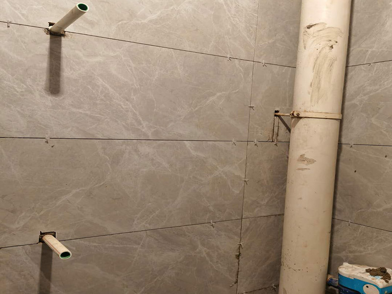 衛(wèi)生間貼磚施工：應(yīng)全部清理墻面上的各類污物，打掃干凈現(xiàn)場(chǎng)，特別是腳落里。用泥刀先批墻，后用水泥漿找平。這個(gè)工序很重要，確保底子平，防止貼后空鼓。墻面要刷防水涂料，防止貼后浸水，一般高度不低于1.8米，刷的時(shí)候會(huì)稍高一些。根據(jù)設(shè)計(jì)鋪貼圖樣的要求，確定排磚方案，用墨斗彈線，以減少施工損耗。把剛剛攪拌好的粘結(jié)劑漿料均勻的刮到墻上。瓷磚上墻將經(jīng)過(guò)預(yù)先清潔的瓷磚平整地鋪貼在粘結(jié)劑漿料基層上，使用橡膠錘將瓷磚拍實(shí)鋪平。施工過(guò)程中，可小幅度轉(zhuǎn)動(dòng)瓷磚，使?jié){料與瓷磚背面充分接觸。專家建議在鋪貼時(shí)，隨機(jī)取下已鋪貼于基層上的瓷磚作檢查。確保漿料與瓷磚背面的充分接觸。 留縫大小調(diào)整根據(jù)瓷磚的尺寸，在磚與磚之間預(yù)留相應(yīng)尺寸的縫隙留待嵌縫?？捎醚篮灥认裙潭ǎ辰Y(jié)劑具有一定的可調(diào)整性，可對(duì)留縫的大小進(jìn)行調(diào)整。