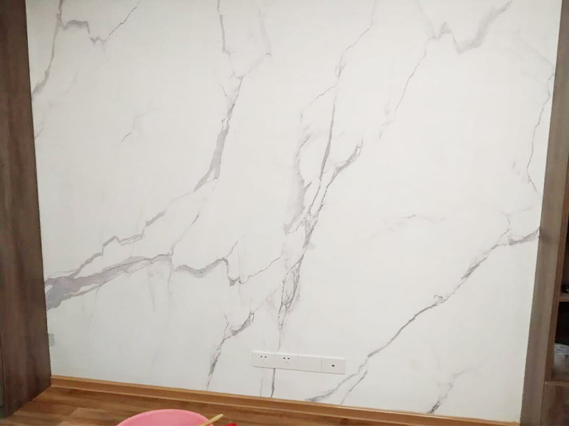 電視背景墻裝修：首先需要量背景墻的尺寸，然后記錄下來，可以去網(wǎng)上或者實體店購買墻布。要注意尺寸要留有余地，才能進(jìn)行處理。要對貼墻布的墻面先進(jìn)行處理，墻面如果是剛做好的水泥漆，干了就可以操作。如果是普通的墻面，需要先做基膜。把購買來的墻布展開，然后站到梯椅上，把墻布對角貼上去。要注意張貼的平整，不能一邊高一邊低。用手按壓住墻布，然后用刮片把墻布刮平。刮角落的時候，要注意用力刮平，不要有褶皺或者翹角。墻布刮好后，要用鋒利的刀片，進(jìn)行修邊處理，電線孔也要用刀片割開。修邊好后，也要用刮片再刮一遍。裁剪邊框的墻紙，按照同樣步驟張貼。張貼好后，用布擦一下，防止膠水沾住。查看張貼效果，關(guān)上窗戶。