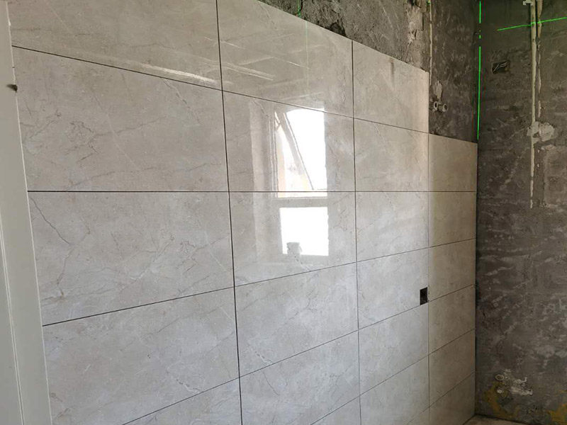 客廳瓷磚鋪貼:鋪貼前，先將所鋪平面表面的塵土、雜物等徹底清掃干凈，平面不能有空鼓、開裂和起砂等現(xiàn)象，如果存在這些現(xiàn)象，要先進(jìn)行修復(fù)處理，在鋪設(shè)瓷磚。鋪設(shè)地磚施工前，要先在地面彈出十字線，從而控制地磚分隔尺寸。然后要選用1:3干硬性水泥砂漿，砂漿的厚度要在25mm左右。把瓷磚按照要求放在水泥砂漿上，用橡皮錘輕輕敲擊瓷磚的表面，直至瓷磚鋪貼平整。鋪貼完瓷磚后，要進(jìn)行勾縫處理，先清理干凈瓷磚縫隙里的雜質(zhì)，再用專用填縫劑進(jìn)行勾縫處理。