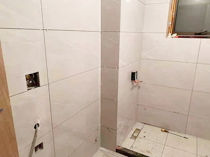 衛(wèi)生間貼磚施工：衛(wèi)生間貼磚要先將所需材料準(zhǔn)備好，一般用在這個(gè)空間的話可以選擇小瓷磚，例如小方塊類型的瓷磚就不錯(cuò)，貼起來也比較方便。然后將水泥與建筑膠混合拌勻，用鏟刀將其鏟到地面刮平再將瓷磚鋪上刀壓實(shí)，這樣按照這樣的方式自上而下或自左而右來進(jìn)行貼磚即可。